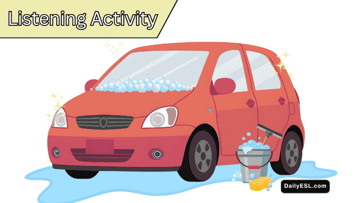 A red car with soap bubbles on it. There is a bucket with cleaning supplies and a puddle of water.